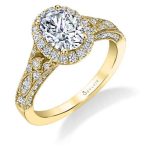 A yellow gold diamond engagement ring from the Sylvie Collection featuring an oval shaped diamond in the center of a halo mounting with milgrain accents and an art deco style