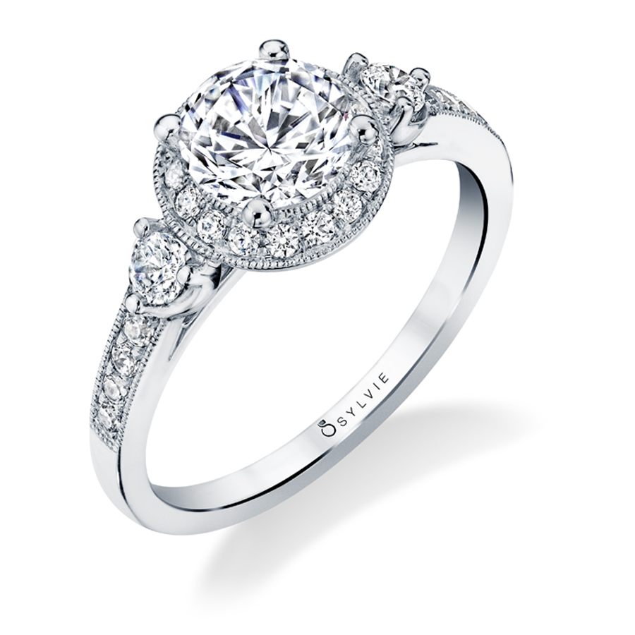 A white gold three stone diamond engagement ring with a halo around the center diamond from the Sylvie Collection