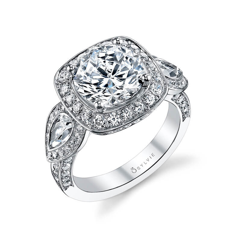 A white gold halo accented three stone style engagement ring with from the Sylvie Collection